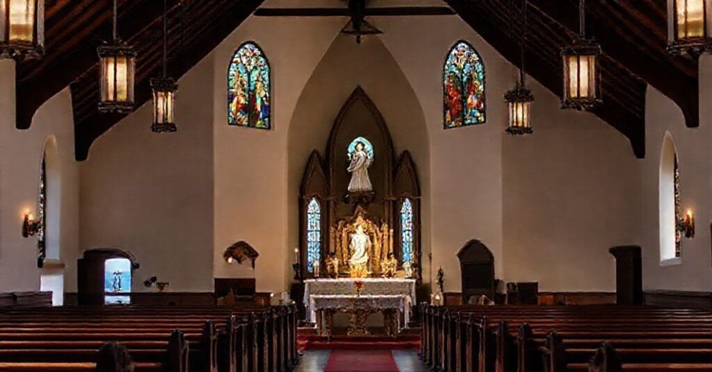 A solemn interior of the Carmel Church of St. Charles Borromeo overlooking the blue sea in California, featuring traditional Catholic architecture and a statue of Our Lady of Bethlehem.